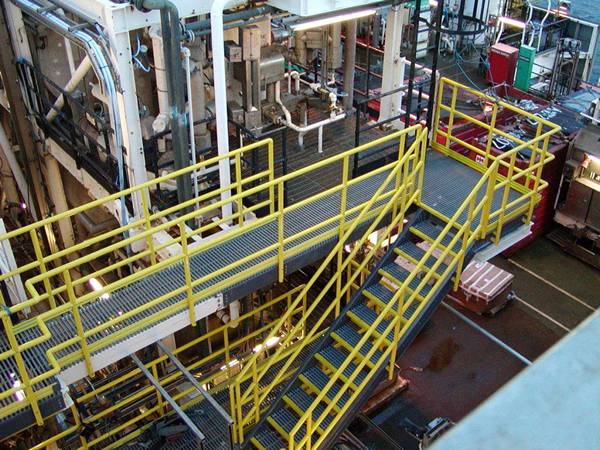 FRP/GRP stair system with yellow handrails and gray stair treads in industries.