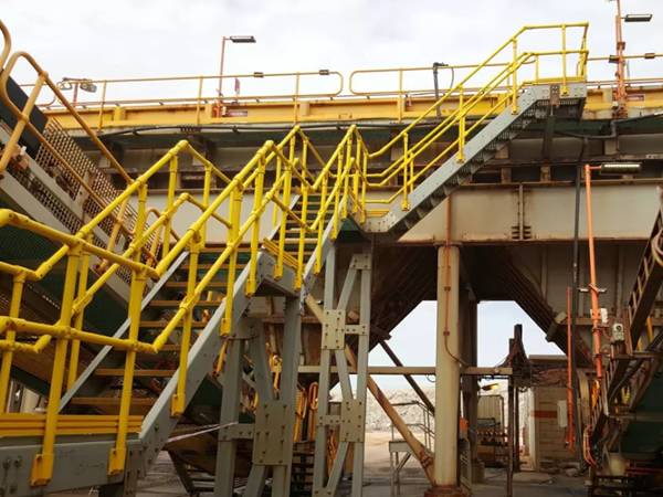 Sistema de escaleras FRP/GRP con pasamanos amarillos y peldaños de escalera amarillos en la fábrica de ingeniería mecánica.