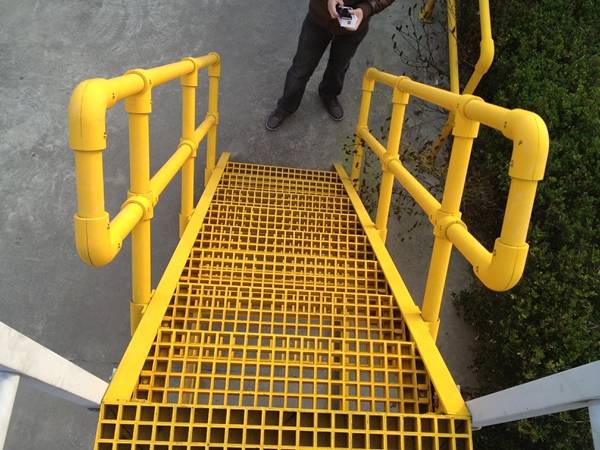 A stair system with round yellow handrails and yellow stair treads.