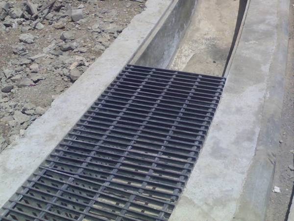 Dark gray trench cover grating is covering trench.