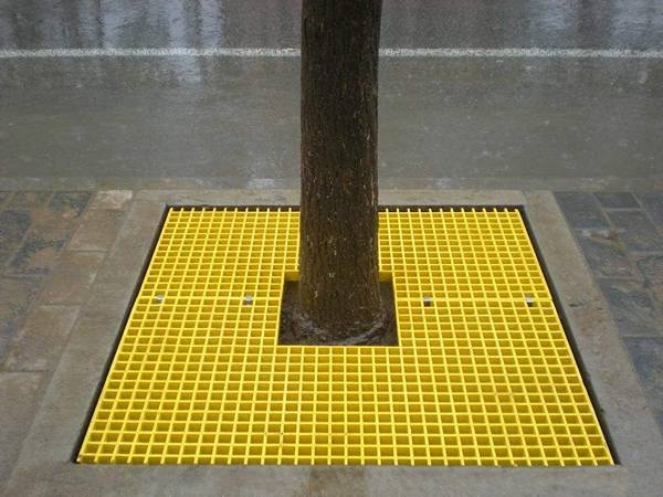 A yellow square tree guard is covering the tree well.